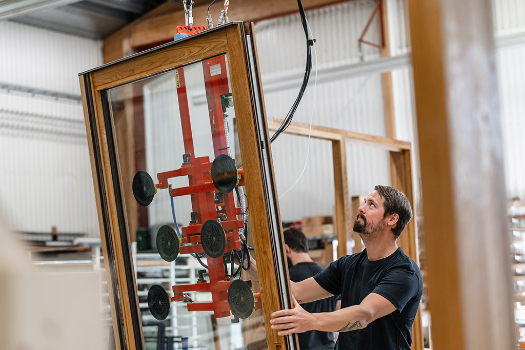 Bild på medarbetare i fabriken. Hanterar fönster.